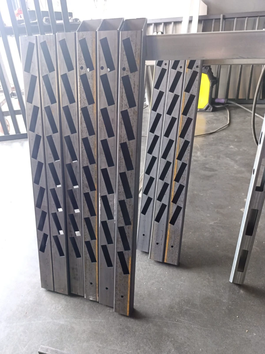 Pionowe profile stalowe z ukośnymi wykrojami powstałymi w procesie cięcia laserowego