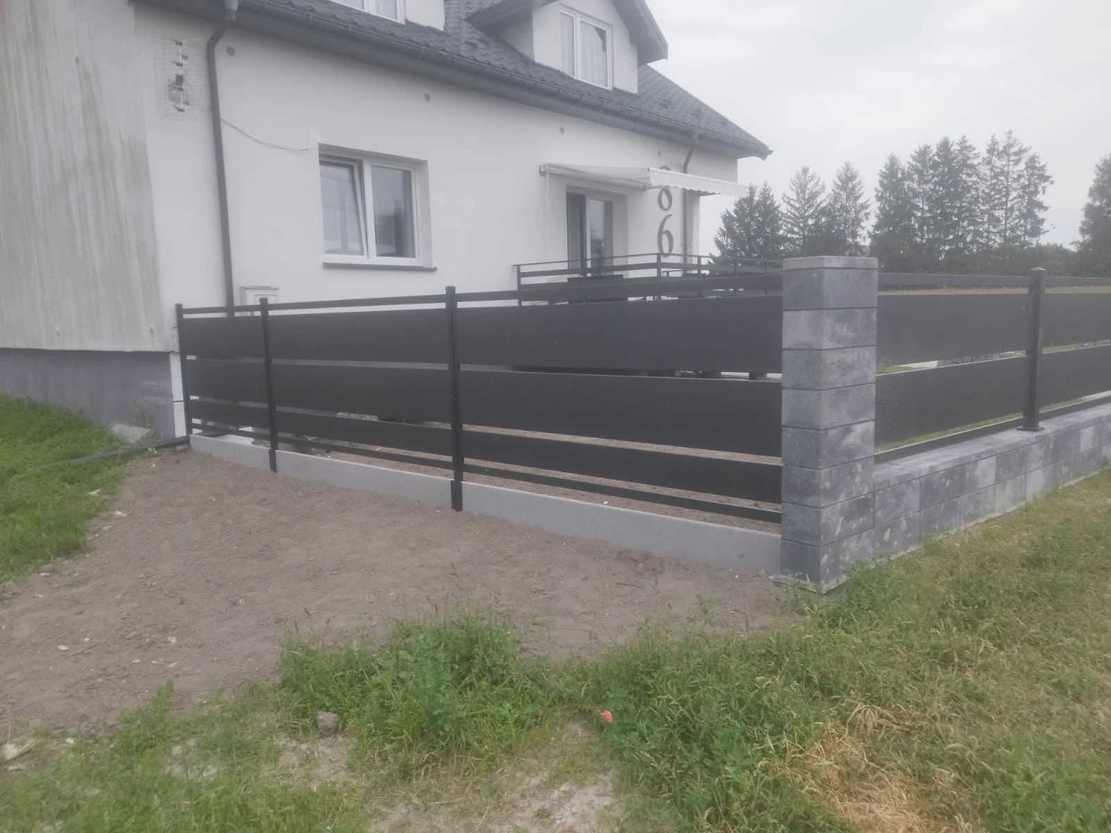 Ogrodzenie żaluzjowe z poziomych stalowych lameli na kamiennej podmurówce