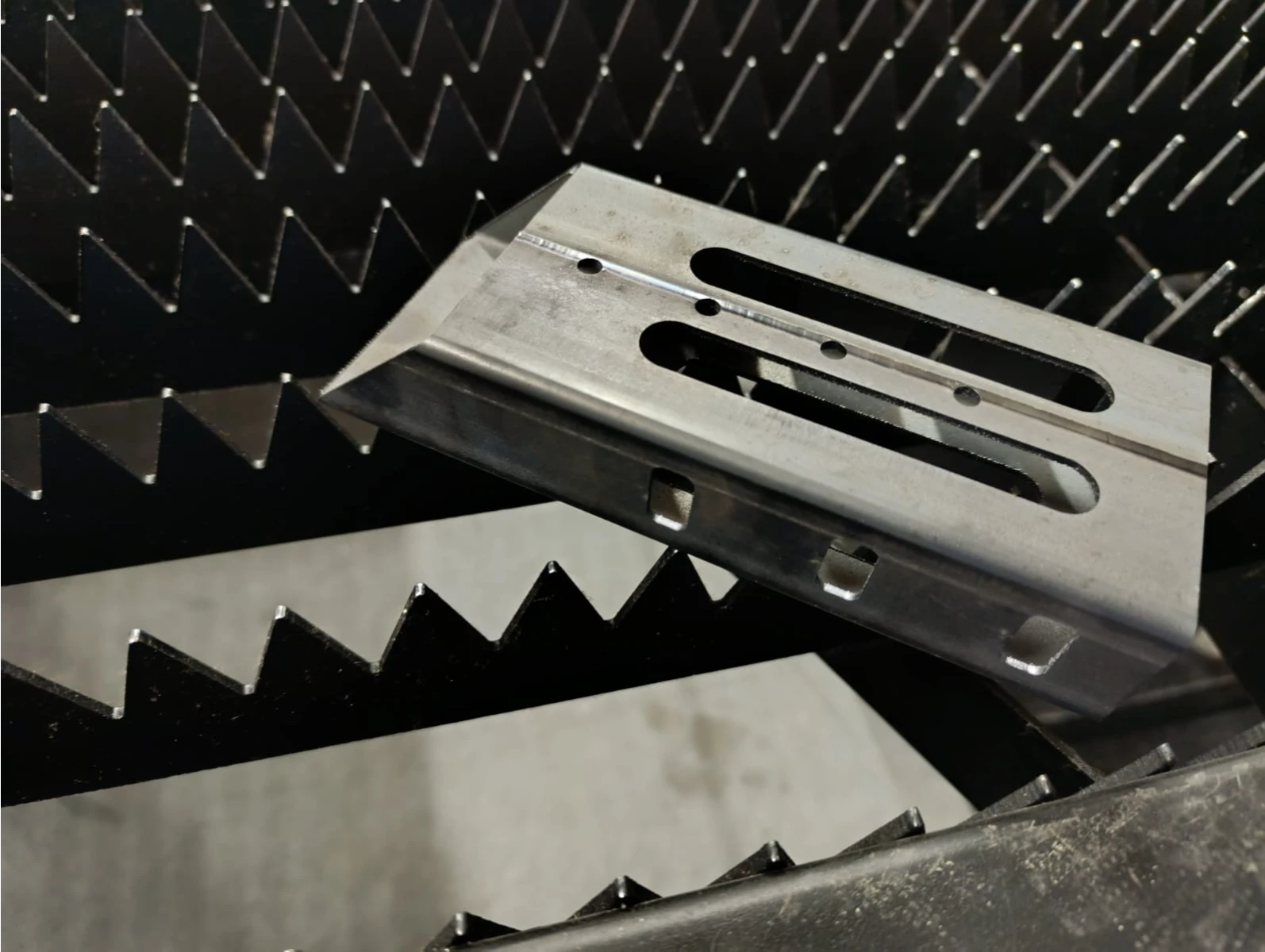 Metalowy profil z wydłużonymi otworami na stole do cięcia laserowego Cięcia laserowe